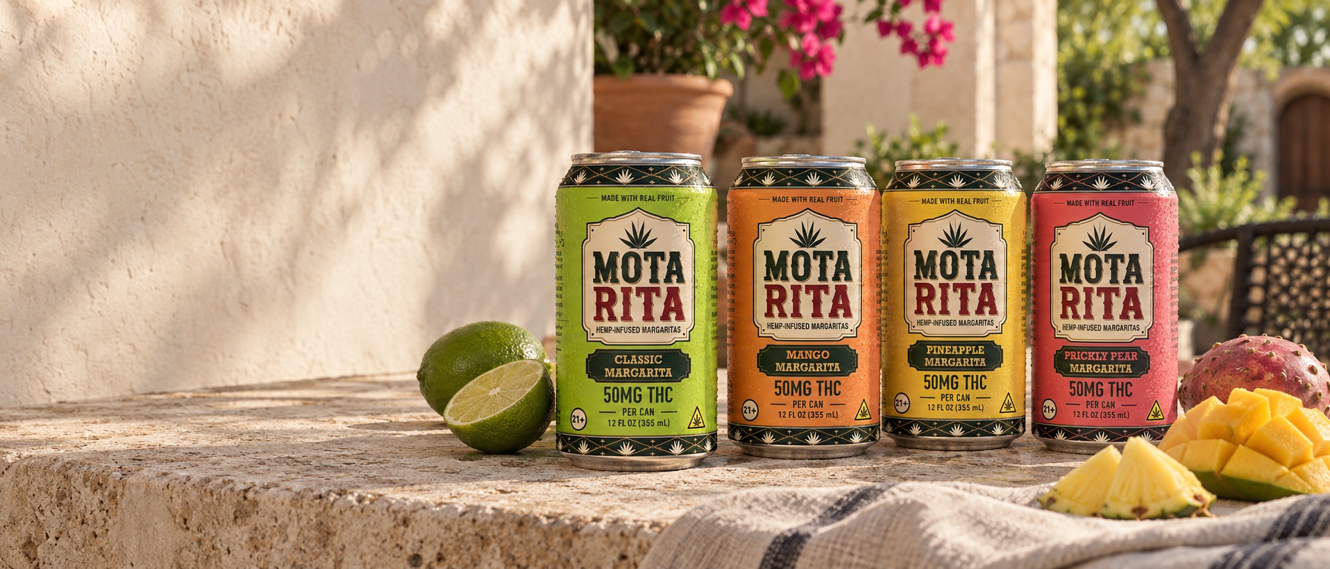 Classic, Mango, Pineapple and Prickly Pear MotaRita cans on a sunlit stone patio with fresh fruit